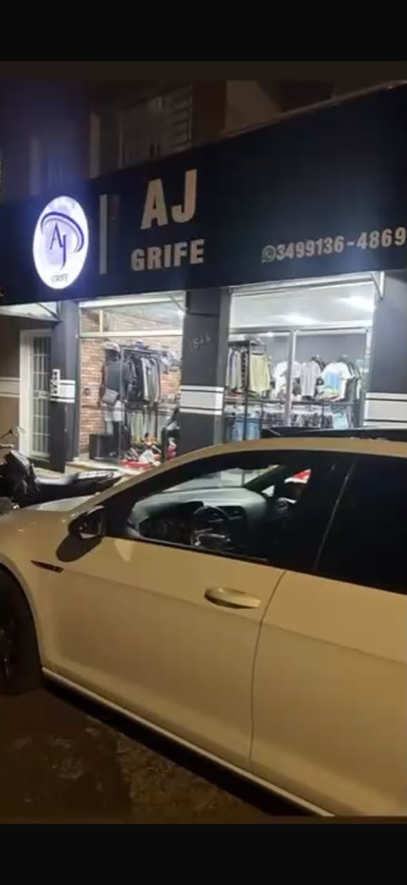 Fachada iluminada da loja AJ Grife durante a noite